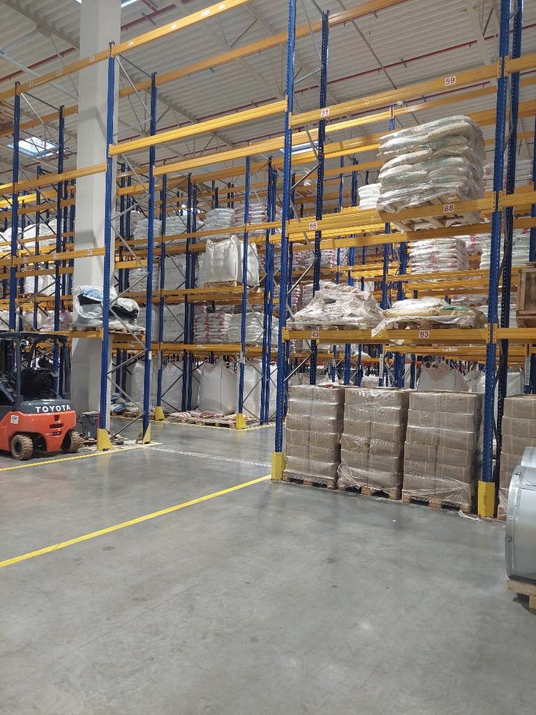 Forklift operating among warehouse racks and palletized goods